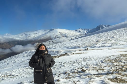 Young latina woman posing with black jacket on snowy mountain very happy, free, full, positive, enjoy life