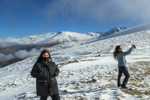 two Latin women enjoy a winter day in sierra nevada,granada, taking a selfie with a smartphone
