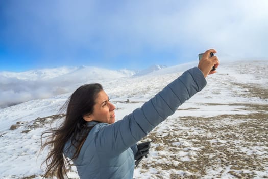 Latina woman taking a selfie with a smartphone while enjoying a winter day in sierra nevada,granada,