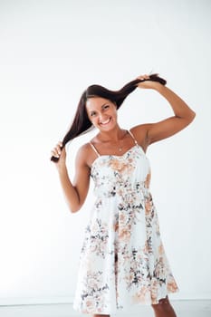 Brunette in floral dress posing on white