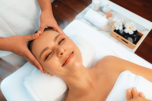 Caucasian woman enjoying relaxing anti-stress head massage and pampering facial beauty skin recreation leisure in dayspa modern light ambient at luxury resort or hotel spa salon. Quiescent