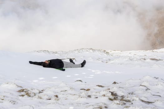 young Latin boy, lying in the snow, in the middle of a blizzard