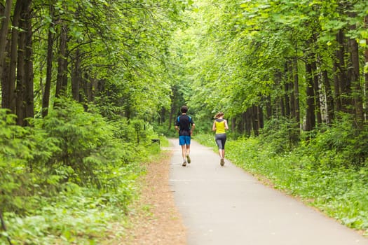 fitness, sport, friendship and lifestyle concept - smiling couple running outdoors