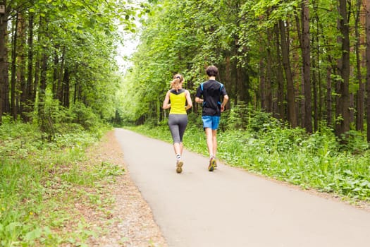 fitness, sport, friendship and lifestyle concept - smiling couple running outdoors