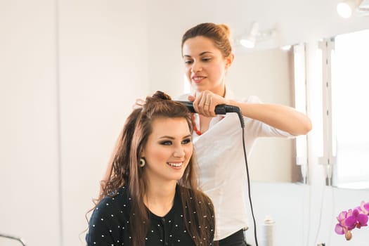 Woman at hairdresser with iron hair curler