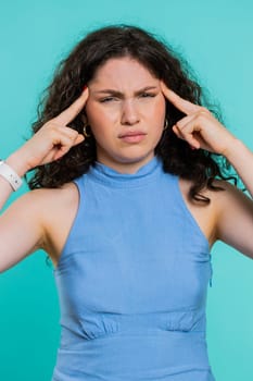 Attractive exhausted young woman girl rubbing temples to cure headache problem, suffering from tension, migaine, stress, grimacing in pain, high blood pressure isolated on blue background. Vertical