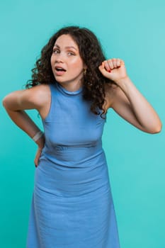 Knock-knock who is there. Excited young woman knocking door gesture asking who is at home, feeling embarrassed, no idea, being clueless and uncertain. Girl alone on studio blue background. Vertical