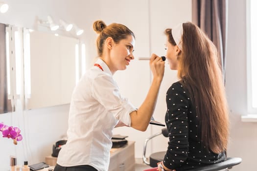 Make-up artist doing make up for young beautiful woman.