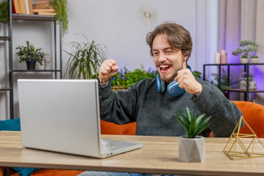Surprised Caucasian man using laptop computer, receive mail good news message shocked by sudden victory celebrate lottery jackpot win purchases online shopping play game at home apartment at table