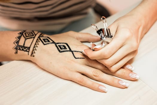 Artist applying henna tattoo on women hands. Mehndi is traditional Indian decorative art. Close-up.