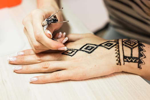 Artist applying henna tattoo on women hands. Mehndi is traditional Indian decorative art. Close-up.