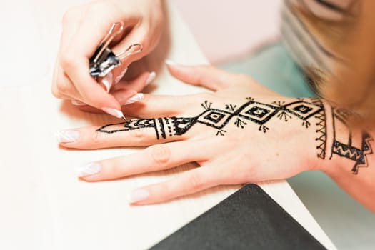 Artist applying henna tattoo on women hands. Mehndi is traditional Indian decorative art. Close-up.