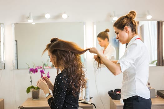 working day inside the beauty salon. Hairdresser makes hair styling