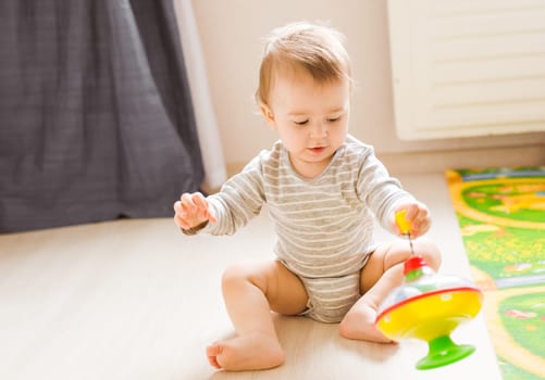 baby boy playing with toy indoors at home.