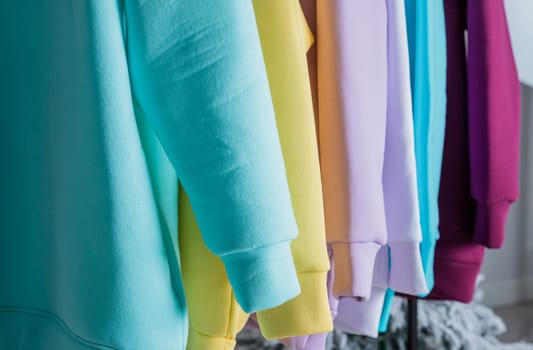 Sweatshirts on hangers in the clothing store for sale. Row of colorful cashmere hoodies for youth.