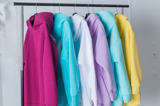 Sweatshirts on hangers in the clothing store for sale. Row of colorful cashmere hoodies for youth.