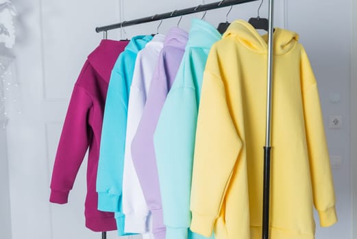 Sweatshirts on hangers in the clothing store for sale. Row of colorful cashmere hoodies for youth.