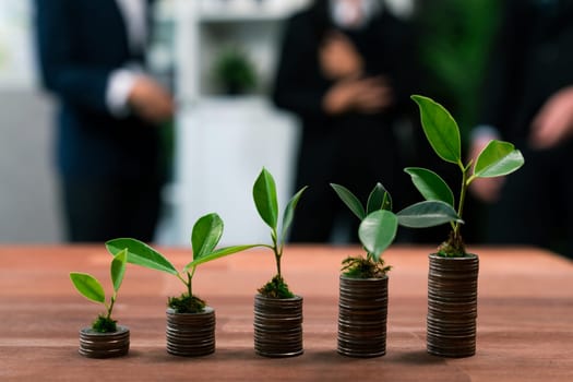 Organic money growth investment concept shown by stacking piles of coin with sprout or baby plant on top. Financial investments rooted and cultivating wealth in harmony with nature. Quaint