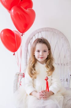 girl sits with red heart balloons