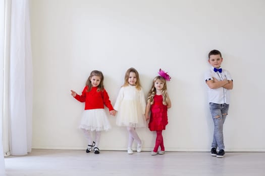 Boy and little girls stand at the white wall