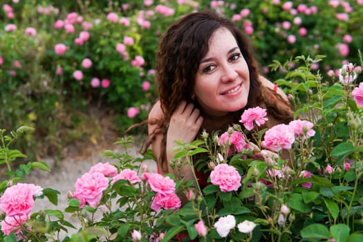 Beautiful woman in dress on a field of blossoming roses