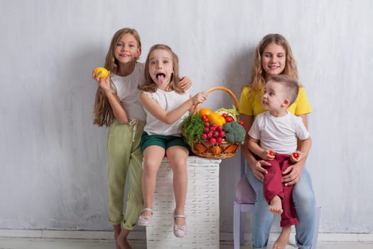 Girls and boy hold vegetables and fruits
