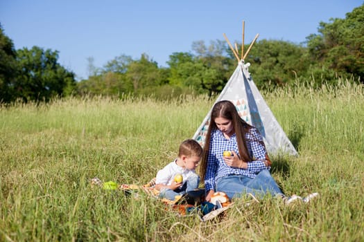 Mom and son eat in park picnic in nature