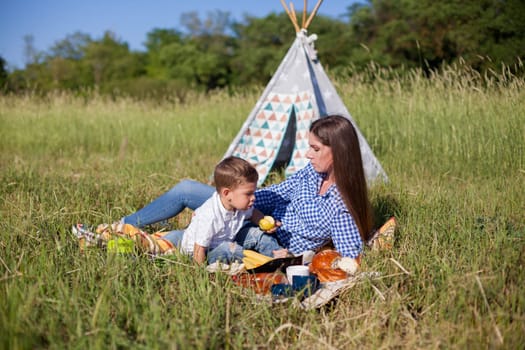 Mom and son eat in park picnic in nature