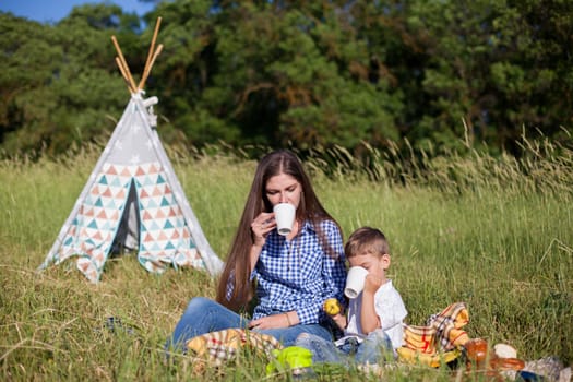 Mom and son eat in park picnic in nature