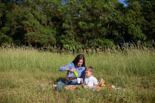 Mom and son eat in park picnic in nature