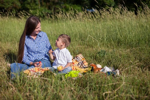 Mom and son eat in park picnic in nature