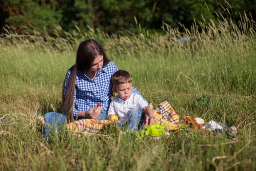 Mom and son eat in park picnic in nature