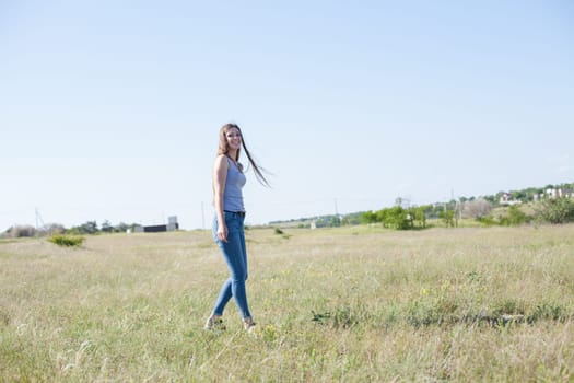 woman walks in a field in the park and smiles