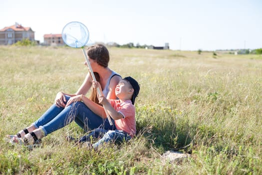 Mom and son catch butterflies in field on walk