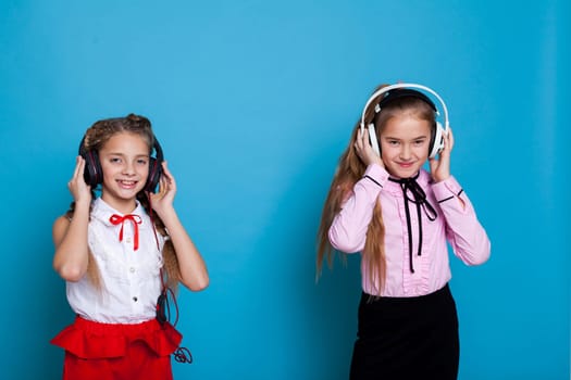 Two schoolgirl girls listen to music with headphones
