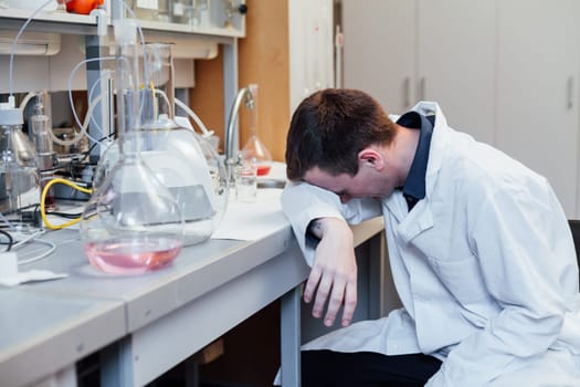 Male scientist tired of wanting to sleep after chemical experiments in lab