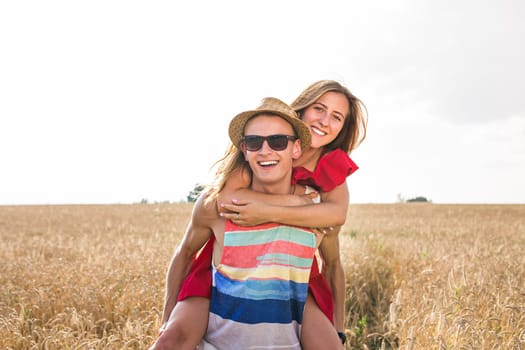 Couple Having Piggyback In Summer Harvested Field.