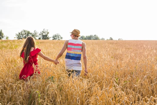 Loving couple holding hands while walking at sunset.