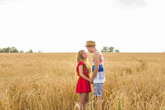 Happy outdoor portrait of young stylish couple in summer in field.