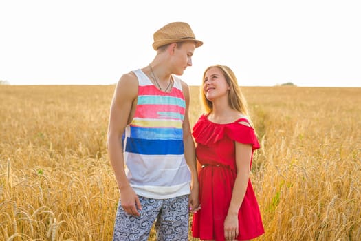 Happy outdoor portrait of young stylish couple in summer in field.