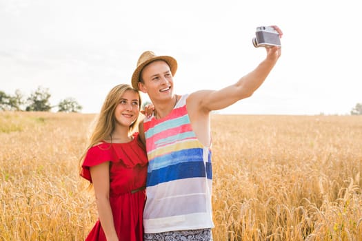 Happy outdoor portrait of young stylish couple in summer in field.