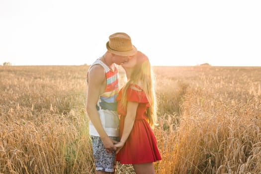 Happy outdoor portrait of young stylish couple in summer in field.