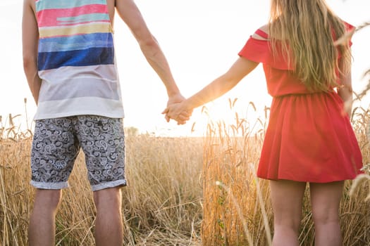 Closeup of loving couple holding hands while walking at sunset.