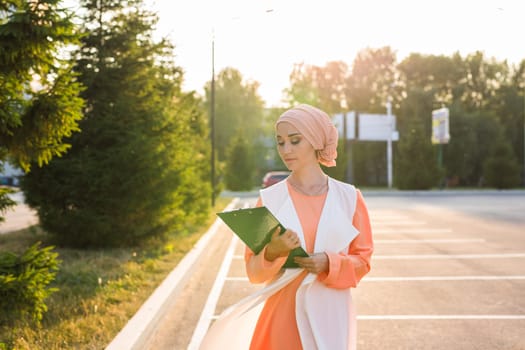 Young Muslim woman standing , holding document paper