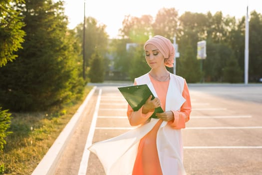 Young Muslim woman standing , holding document paper