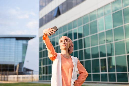 muslim woman taking selfie. girl in abaya on the background of the business center.