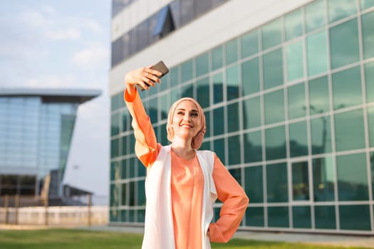 muslim woman taking selfie. girl in abaya on the background of the business center.