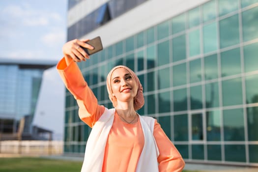 muslim woman taking selfie. girl in abaya on the background of the business center.