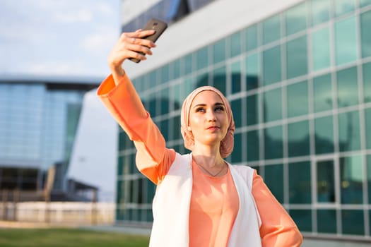 muslim woman taking selfie. girl in abaya on the background of the business center.