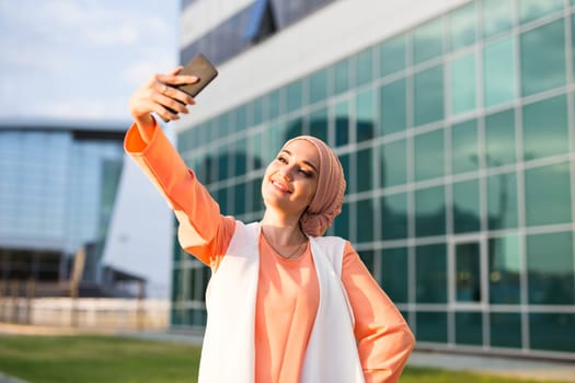 muslim woman taking selfie. girl in abaya on the background of the business center.